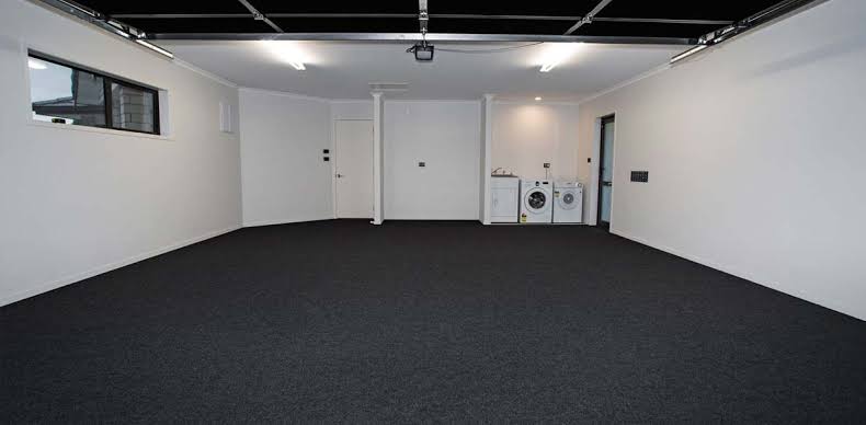 Dark carpet fitted wall to wall in a white garage with laundry appliances at the rear